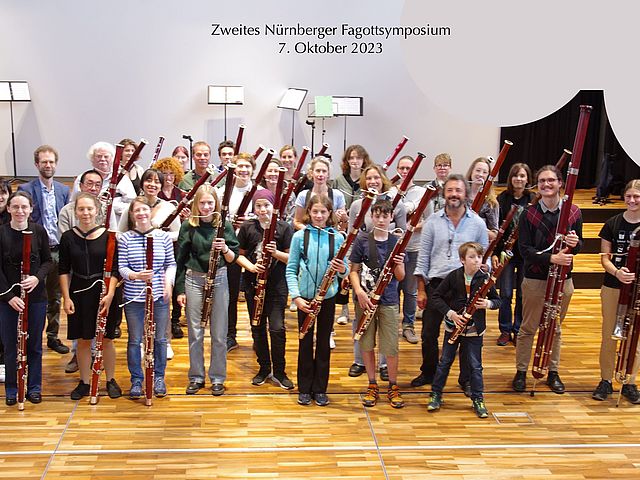 Gruppenbild der Teilnehmer*innen des Fagottsymposiums, die alle ihre Instrumente hochhalten. 